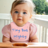 close up of a baby toddler wearing a comical saying bib, 'tiny but mighty'